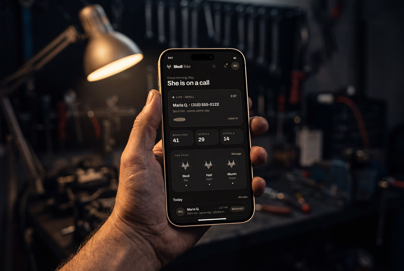 A phone lighting up with a call on a dark workbench